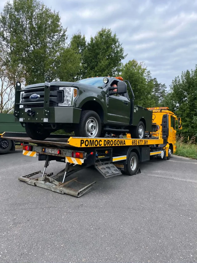 Żółty MAN z zielonym pickupem Ford F-series na platformie